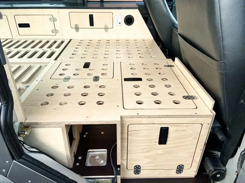 Holzmöbel und Stauraumsystem im Innenraum eines Land Rover Defender Campers
