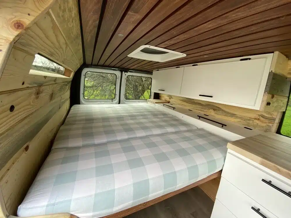 Innenansicht eines ausgebauten Ford E350 Vans mit Bett, Holzverkleidung, Schränken und Stauraum