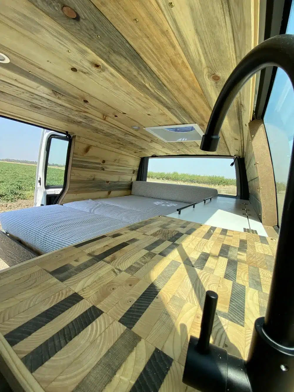 Brooklyn J69JL Campervan Innenraum mit Holzdecke, Arbeitsplatte, Bett und Fensterblick.