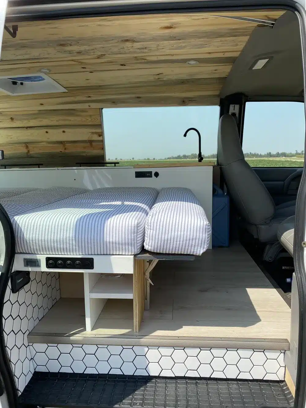 Moderner Innenraum eines Brooklyn J69JL Campervans mit Bett, Holzverkleidung und Stauraum
