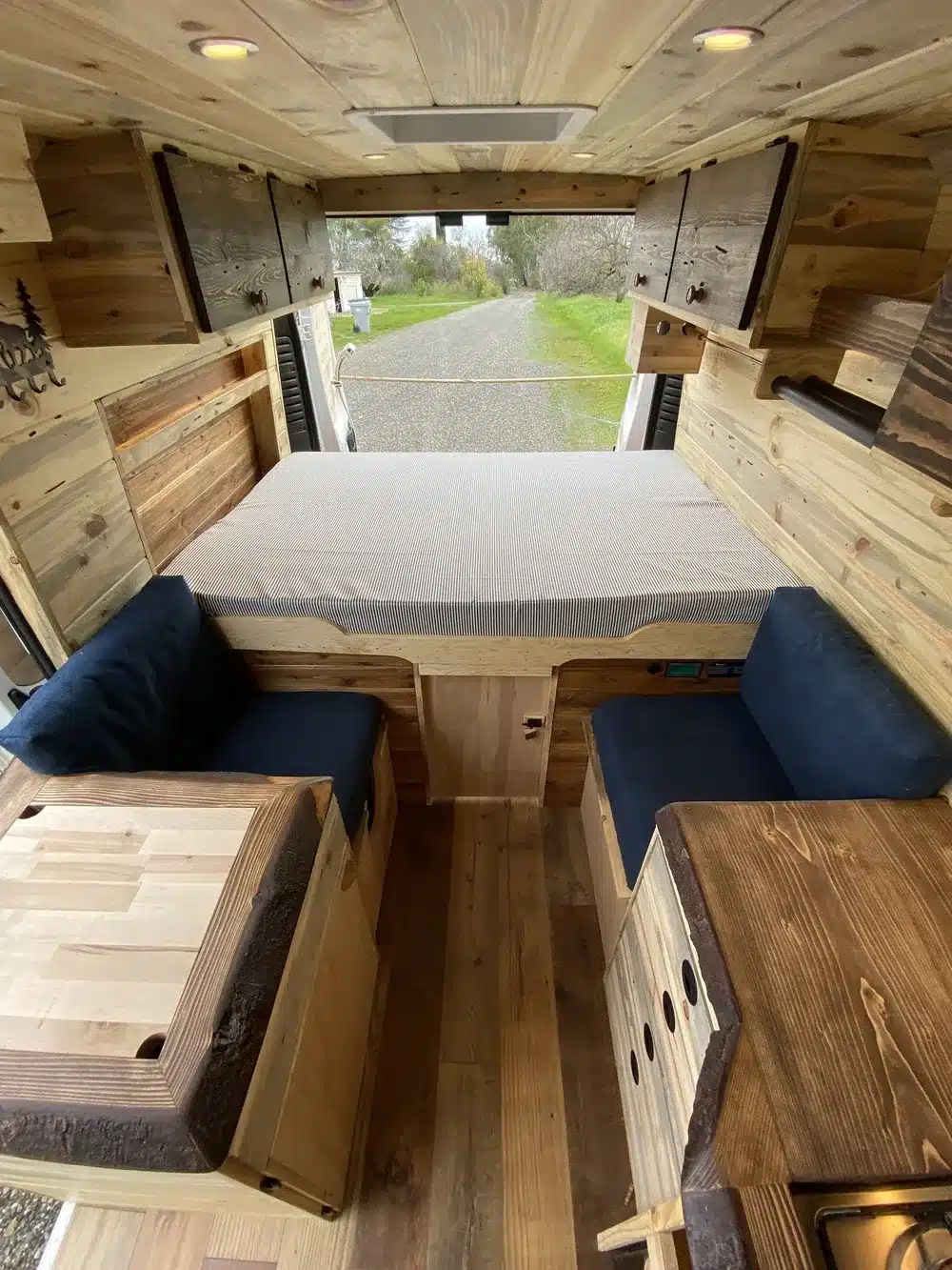 Holzverkleideter Innenraum eines Yolo Cozy Cabin Campers mit Bett und Sitzbereich.