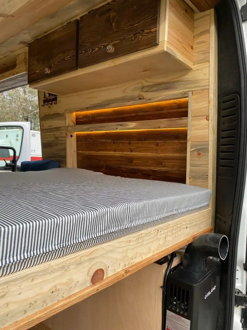 Detaillierte Aufnahme des Innenausbaus im Yolo Cozy Cabin Camper, mit Holzverkleidung, Bett und modernen Stauraumlösungen.