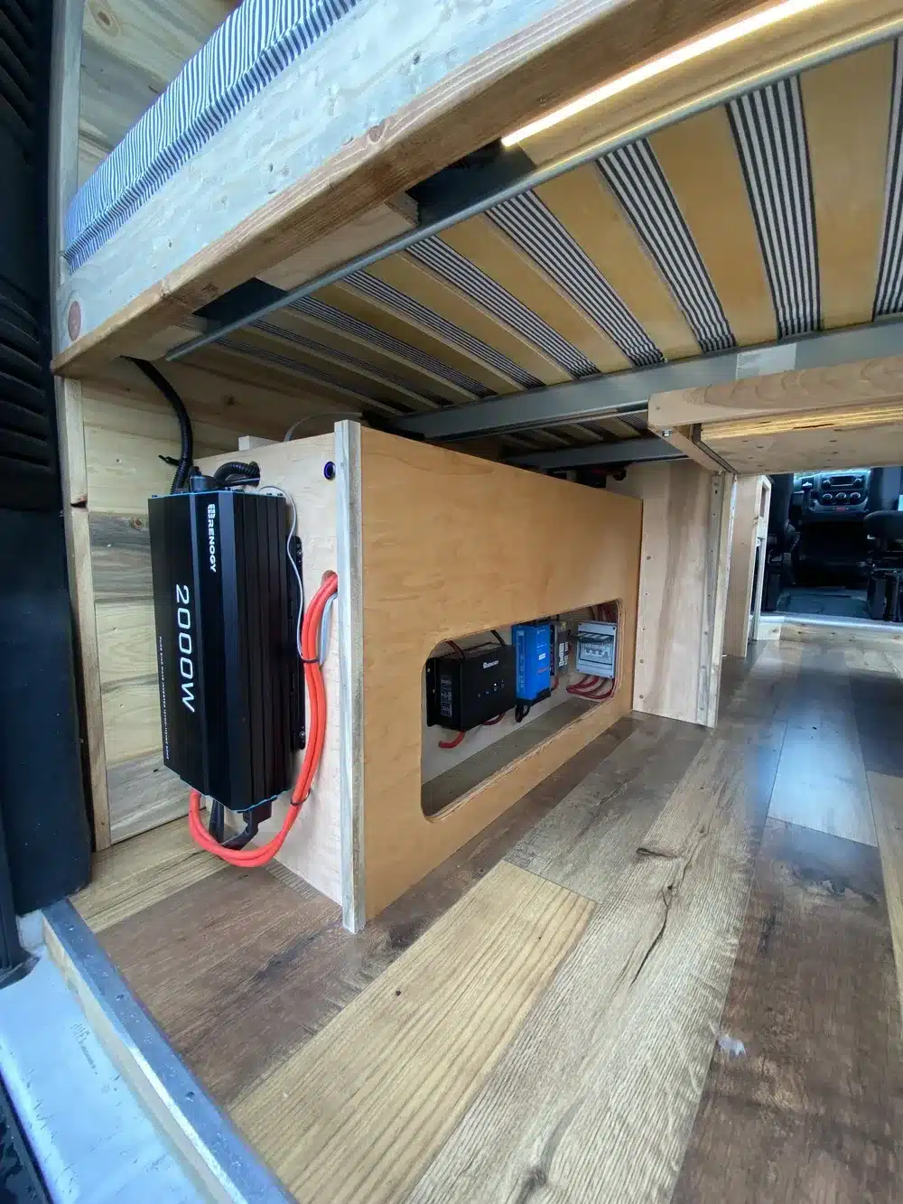 Blick unter das Bett im Yolo Cozy Cabin Camper mit sichtbarer Stromanlage und Stauraum