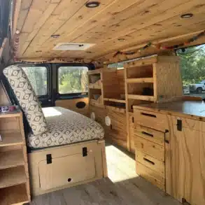 Campervan-Innenraum mit Holzverkleidung, Sitzgelegenheit, Stauraum und Küchenmodul im Donovan von Yolo Campervans.