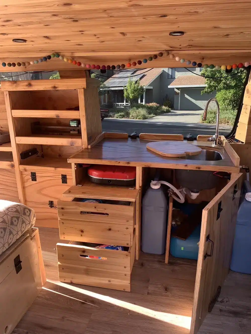 Innenansicht des Donovan Campervans mit ausgebauter Küchenzeile in Holz, Spüle und Stauraum.