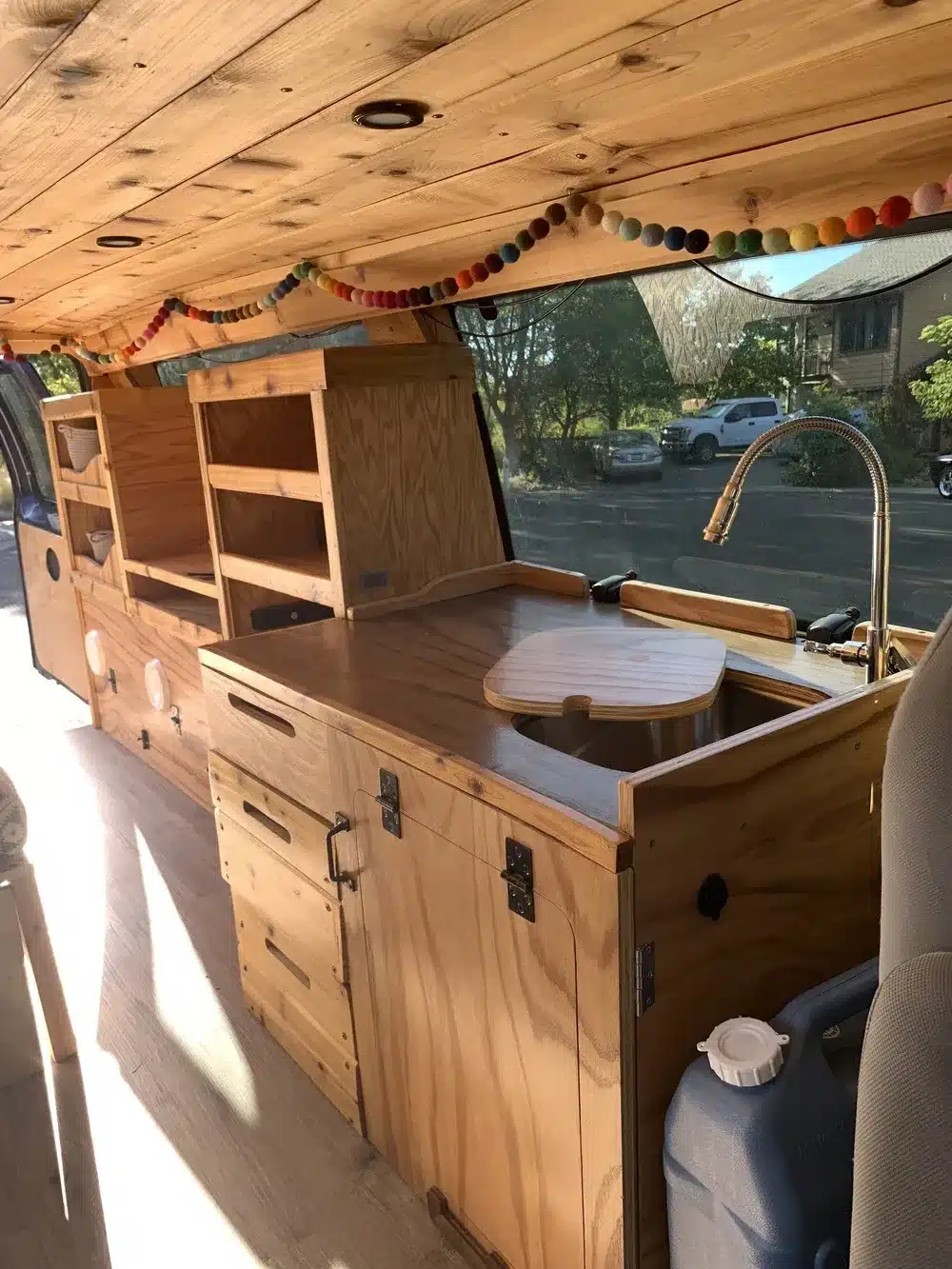 Innenansicht des Donovan Campervans von Yolo Campervans mit Küchenzeile, Stauraum und Holzverkleidung.