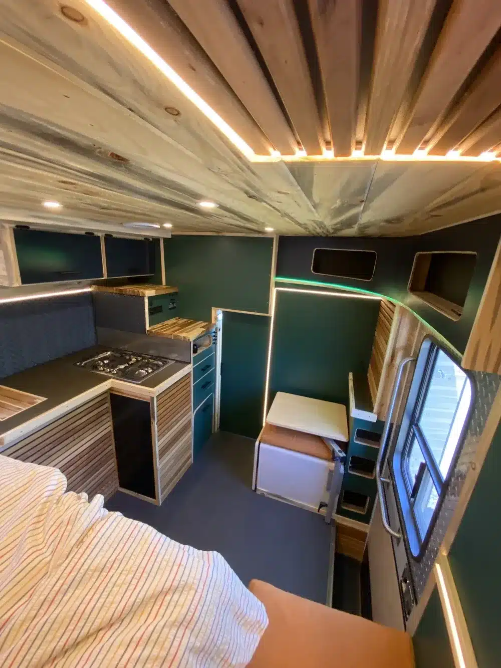 Innenansicht einer Fambulance mit Camper-Ausbau, Holzelementen, Sitz- und Kochbereich.