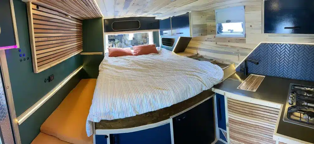 Innenraum eines Campervans auf Rettungswagen-Basis mit Bett, Küchenzeile und Stauraum