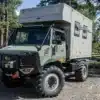 Expeditions-Lkw mit 11-Fuß-Wohnkabine von Bliss Mobil auf Offroad-Gelände, mit Aluminiumrahmen und großem Stauraum.