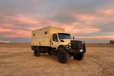 Expeditionsfahrzeug mit 15-Fuß-Kabine auf 4x4-Lkw vor Sonnenuntergang auf offenem Feld
