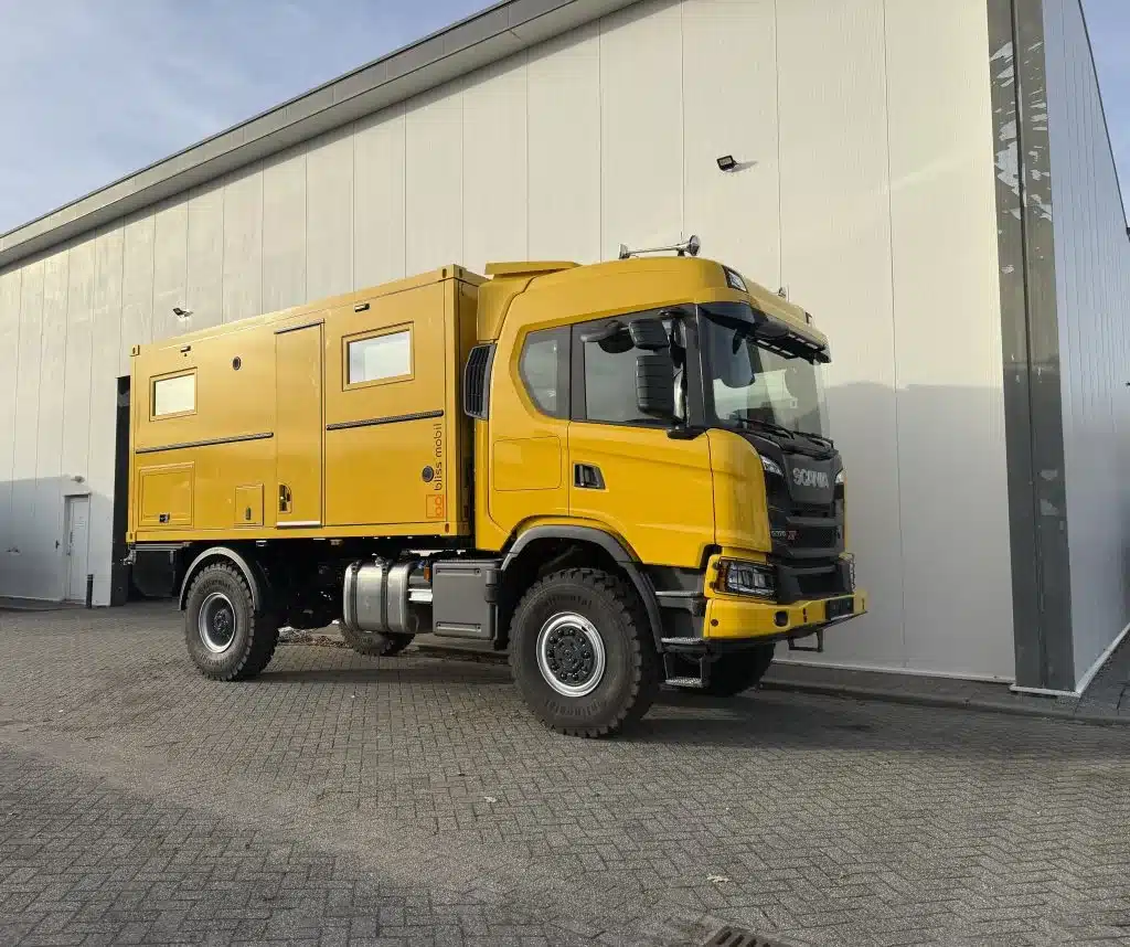Bliss Mobil 16-Fuß-Kabine auf gelbem 4x4-Lkw vor Industriegebäude