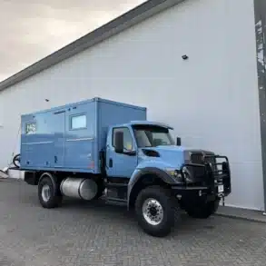Bliss Mobil 16-Fuß-Expeditionskabine auf einem blauen 4x4-Lkw vor moderner Halle