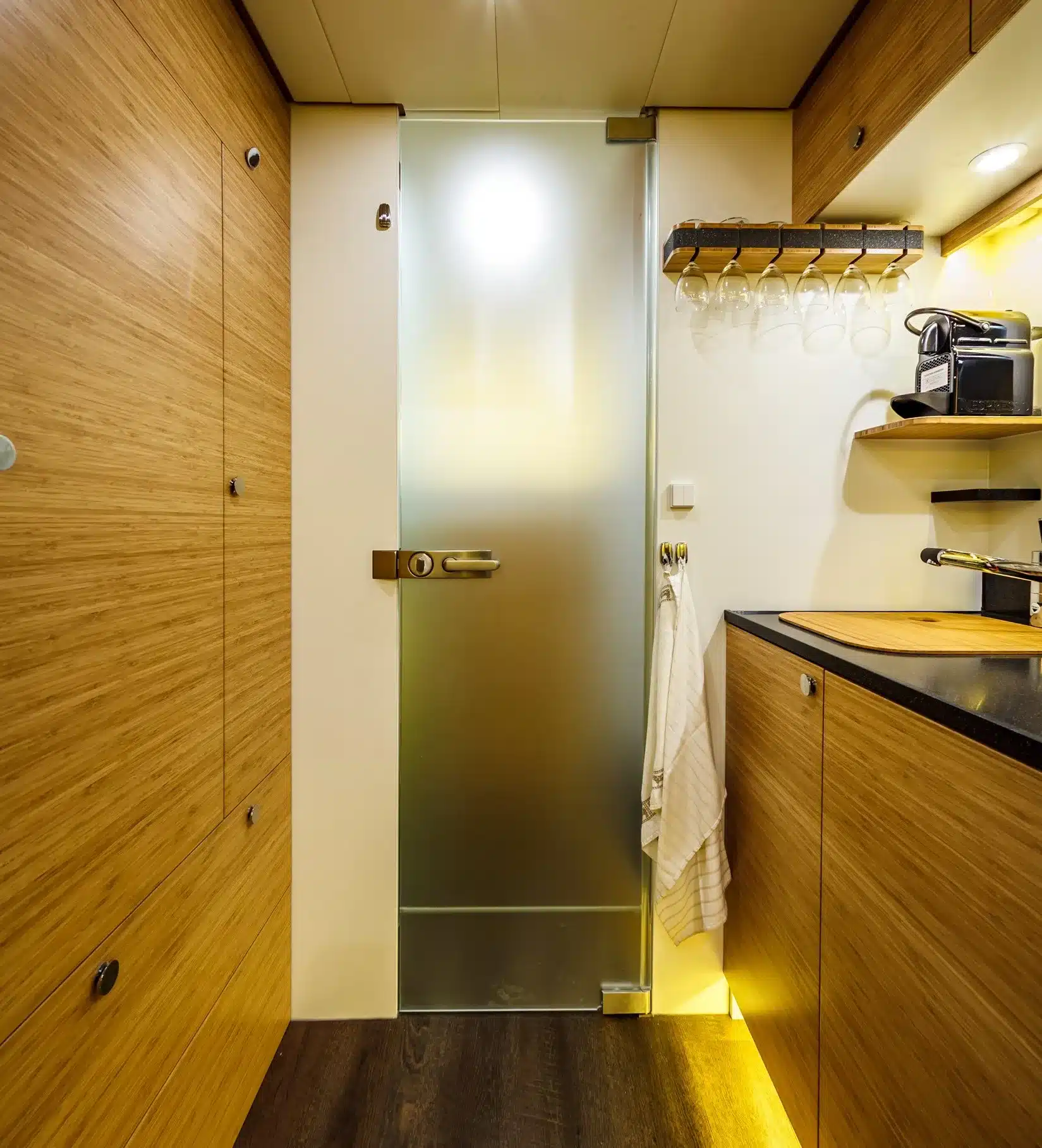 Innenansicht der Bliss Mobil 16-Fuß Expeditionskabine mit Küchenzeile, Holzverkleidung und Glas-Badtür.