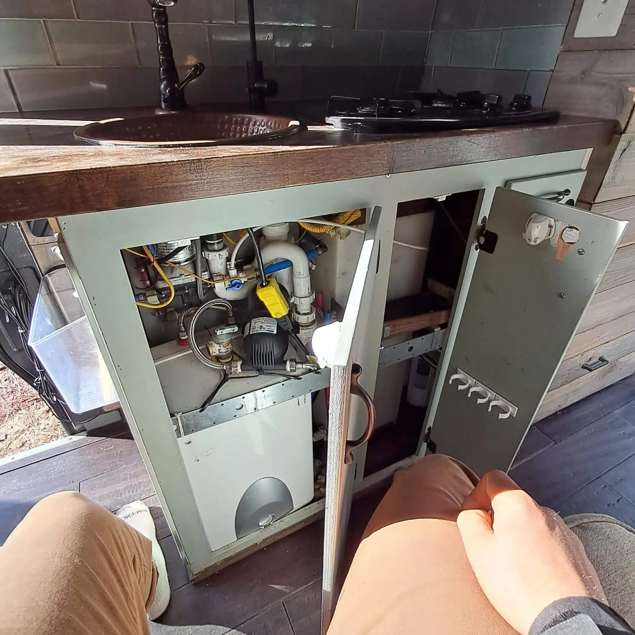 Offener Unterschrank mit Wasseranlage, Pumpe und Boiler im Camping-Van