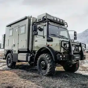 2025 U3 Unimog Expedition Camper im Gelände mit verschneiten Bergen im Hintergrund