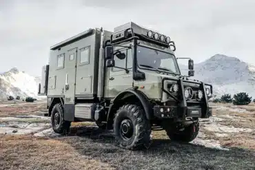 2025 U3 Unimog Expedition Camper im Gelände mit verschneiten Bergen im Hintergrund