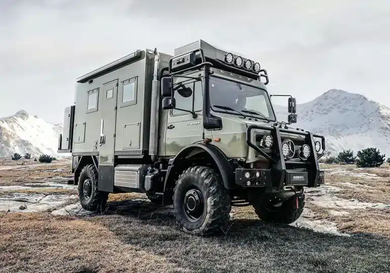 2025 U3 Unimog Expedition Camper im Gelände mit verschneiten Bergen im Hintergrund