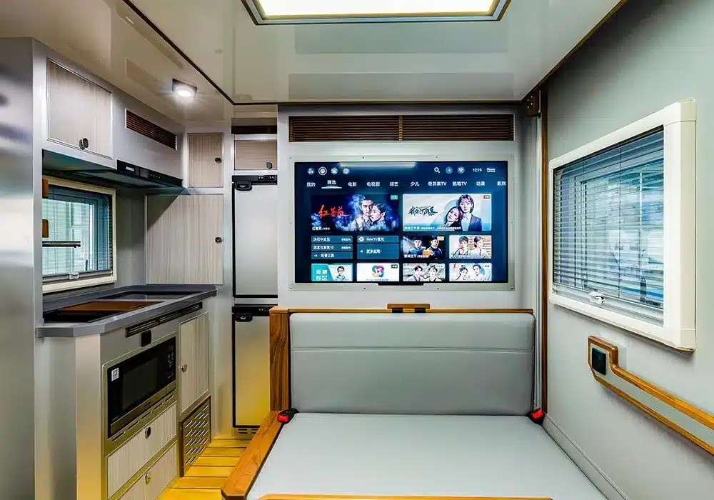 Innenausstattung eines Expeditionscampers mit Küchenzeile, Sitzgelegenheit und großem Bildschirm