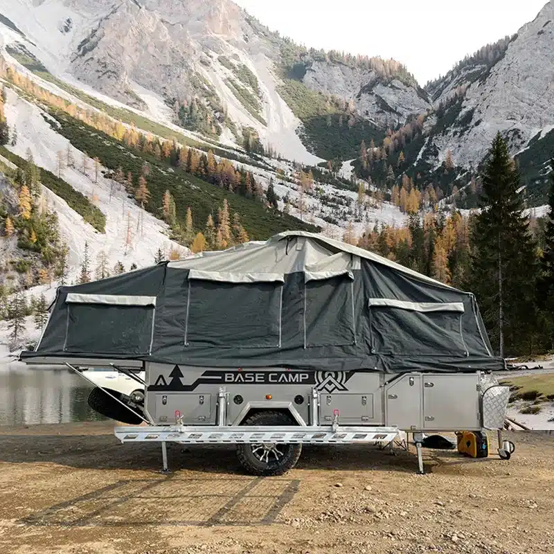 Aufgebauter Base Camp 3C Offroad Zeltanhänger im Gebirge mit Bergen und verschneiten Hängen im Hintergrund
