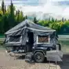 Base Camp 3D Tent Offroad-Camper Trailer mit Zeltaufbau und ausgezogener Außenküche vor See und Waldlandschaft