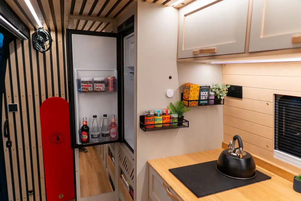 Innenraumansicht der Küche mit geöffnetem Kühlschrank im Beyond 2 Mercedes Sprinter Campervan