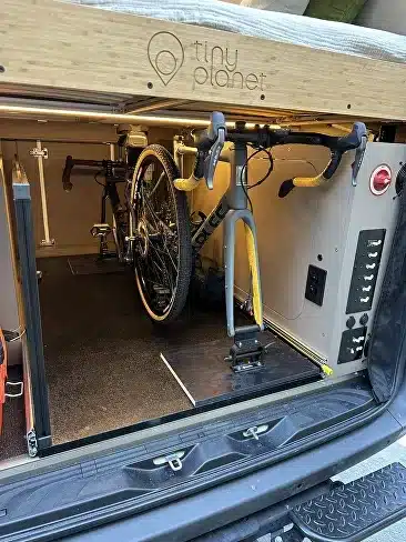 Fahrrad im hinteren Stauraum eines Camping-Vans mit Technikpanel.
