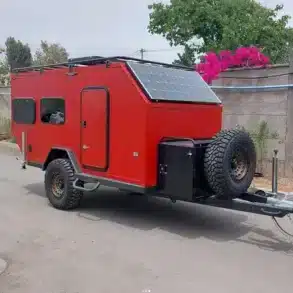 Roter Black Rhino MINI 2B MAX Offroad-Caravan mit Solarpanel und Ersatzrad auf Asphaltstraße