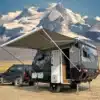 Black Rhino T11 Offroad-Caravan mit Markise vor schneebedecktem Berg, angehängt an ein Geländefahrzeug.
