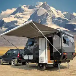 Black Rhino T11 Offroad-Caravan mit Markise vor schneebedecktem Berg, angehängt an ein Geländefahrzeug.
