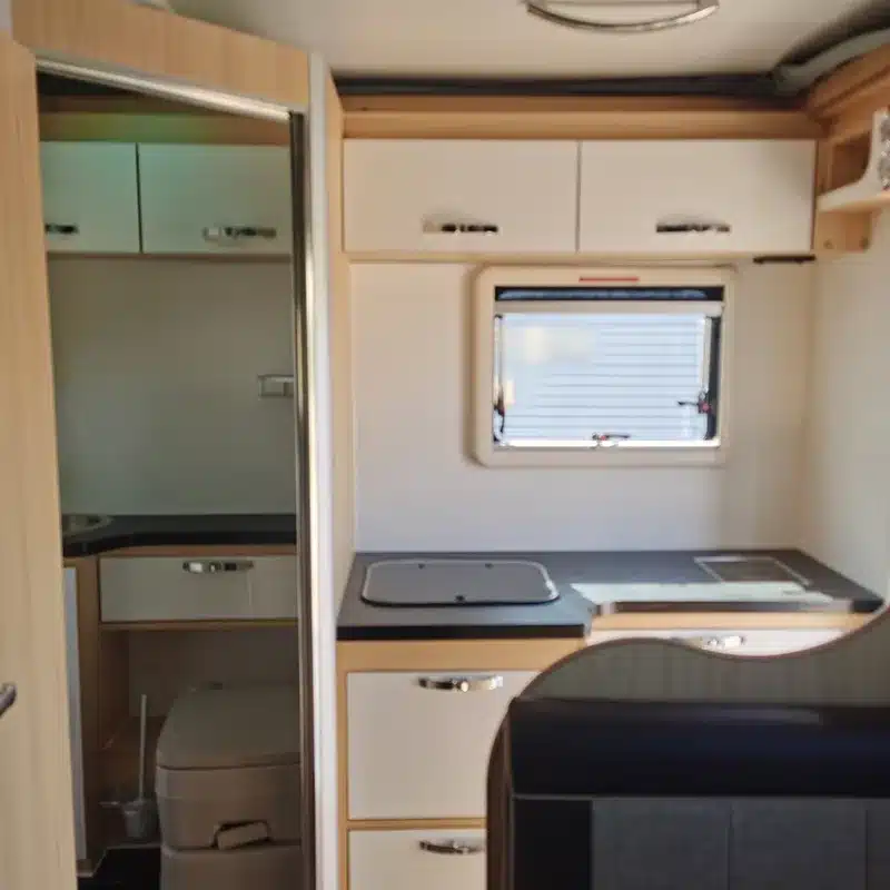 Blick in den Innenraum des Black Rhino T12 Offroad-Caravans mit Küchenbereich, Fenster und WC.