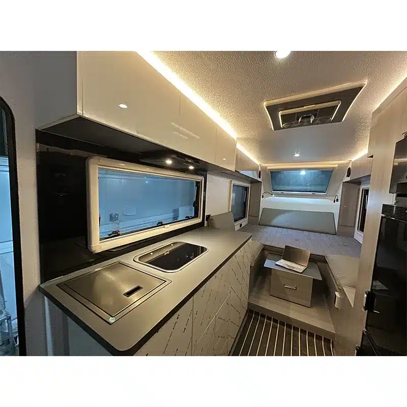Innenansicht des Black Rhino T19 Offroad-Caravans mit Küche, Sitzgruppe und Bett.