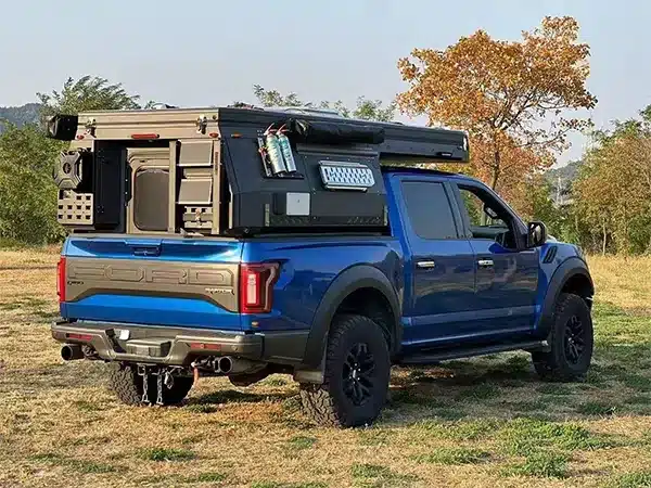 Pickup mit montiertem Black Stone Ilmenite Camper und ausgeklapptem Zubehör am Feldrand.