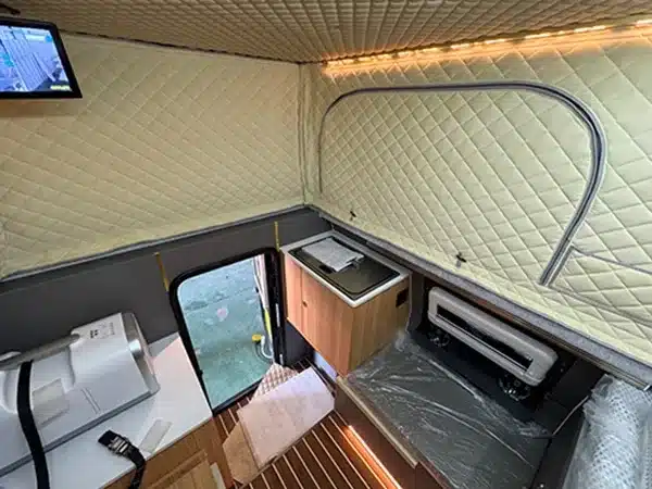 Innenansicht des Black Stone Ilmenite Pickup-Campers mit ausgeklapptem Dach, Küchenecke und Stauraum.