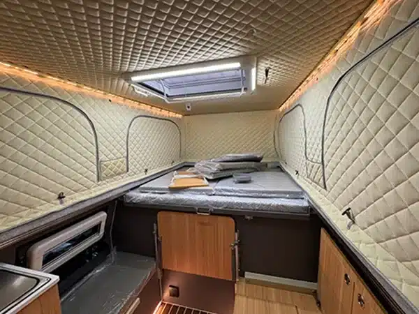 Innenansicht eines Black Stone Ilmenite Pickup Campers mit großem Bett, Stauraum und Küchenzeile.