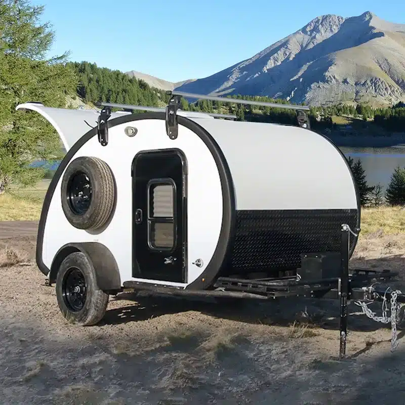 Comma CA Teardrop Camper Trailer auf unbefestigtem Boden in den Bergen bei Sonnenschein.