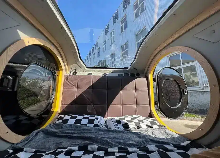 Innenraum des Comma CE Teardrop-Campers mit Bett, Panoramadach und runden Türen