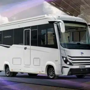 Luxuriöses Reisemobil Concorde Carver in heller Lackierung, Seitenansicht vor moderner Architektur