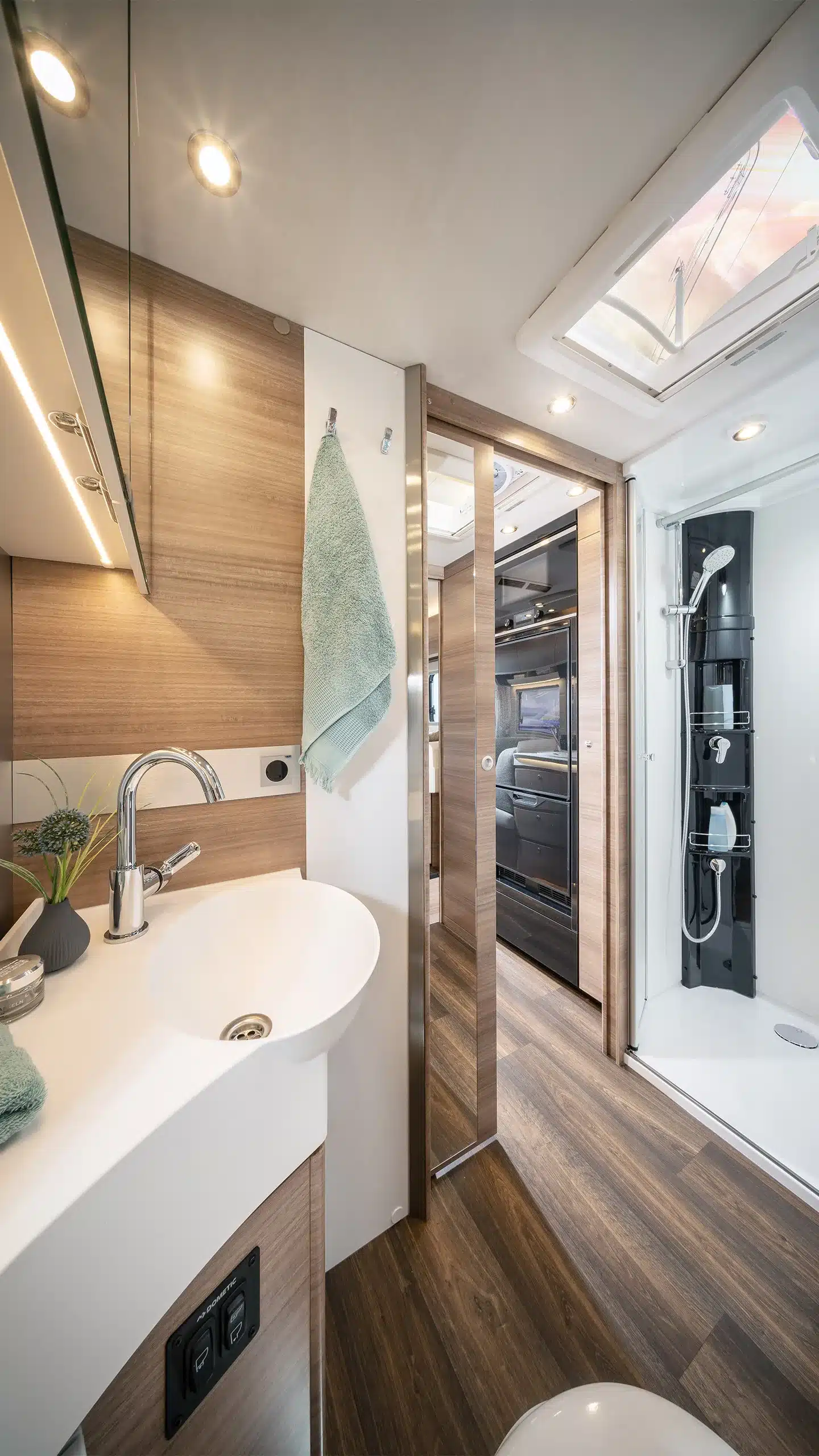 Modernes Badezimmer mit Dusche, Waschbecken und eleganter Holzoptik im Concorde Carver Reisemobil.