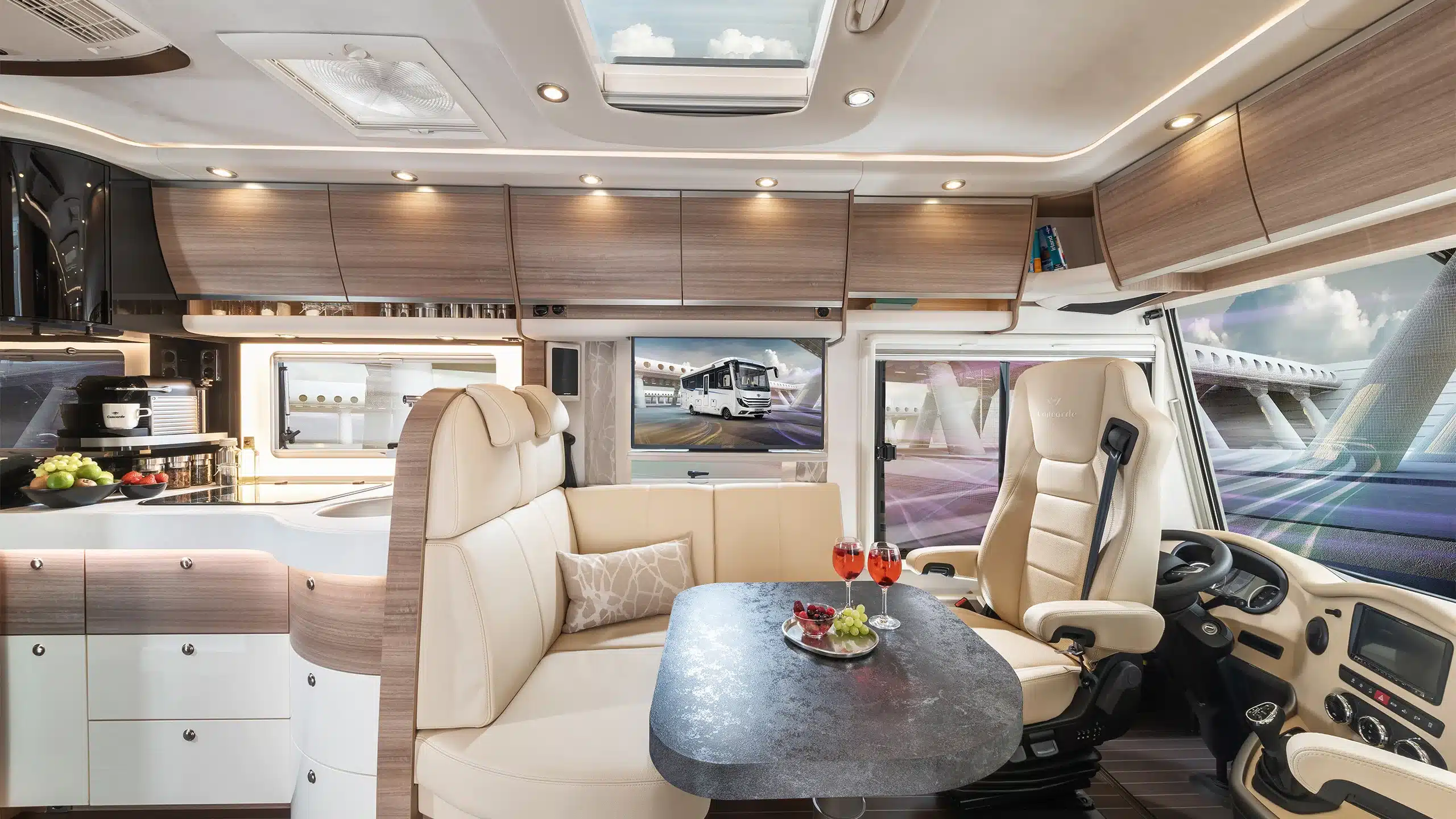 Innenansicht des Concorde Carver Select Reisemobils mit Sitzgruppe, Tisch, Fahrersitz und moderner Küche.