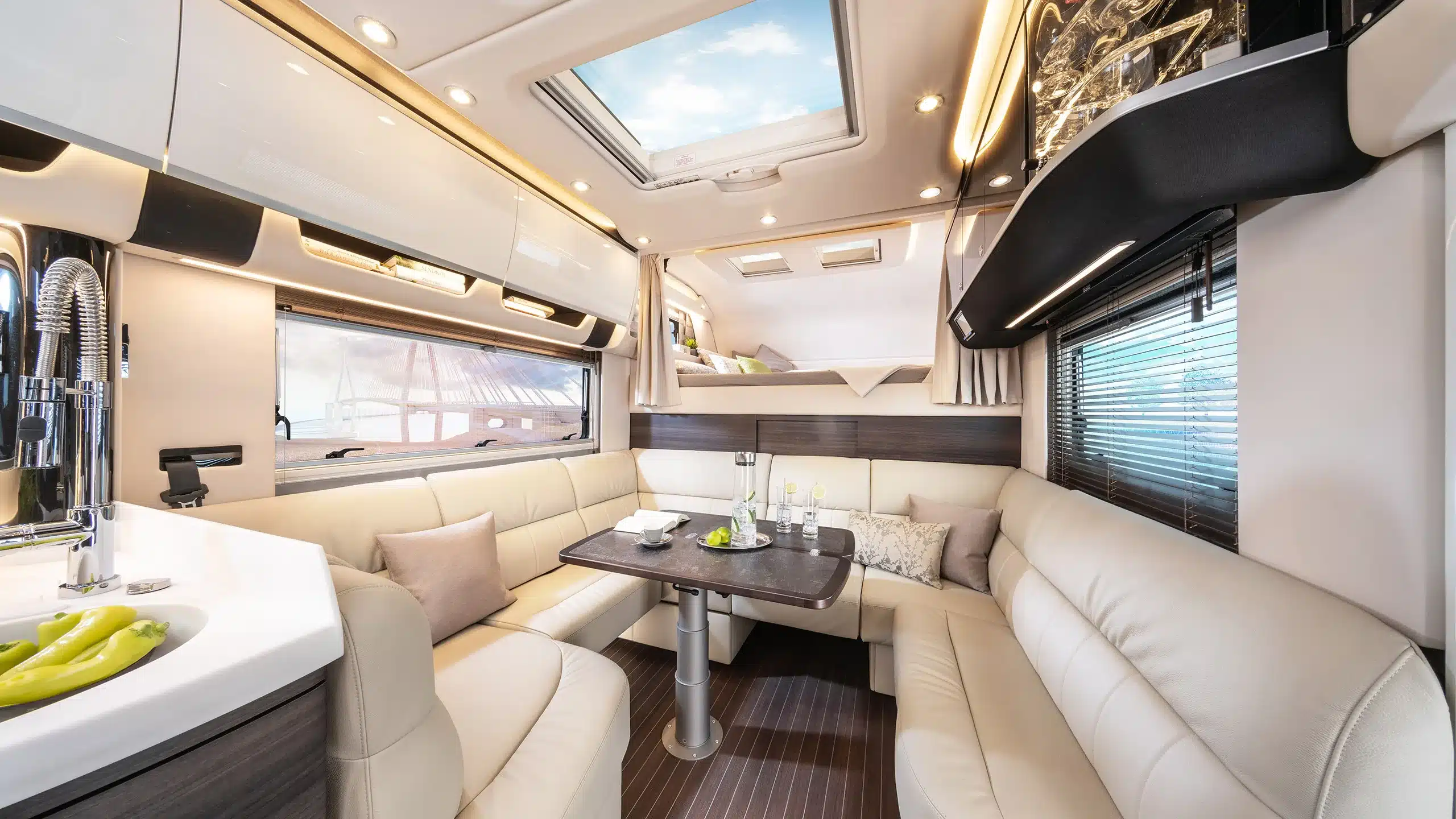 Hochwertig ausgestatteter Innenraum des Concorde Cruiser Atego mit gemütlicher Sitzlounge, Esstisch, Küche und Alkovenbett