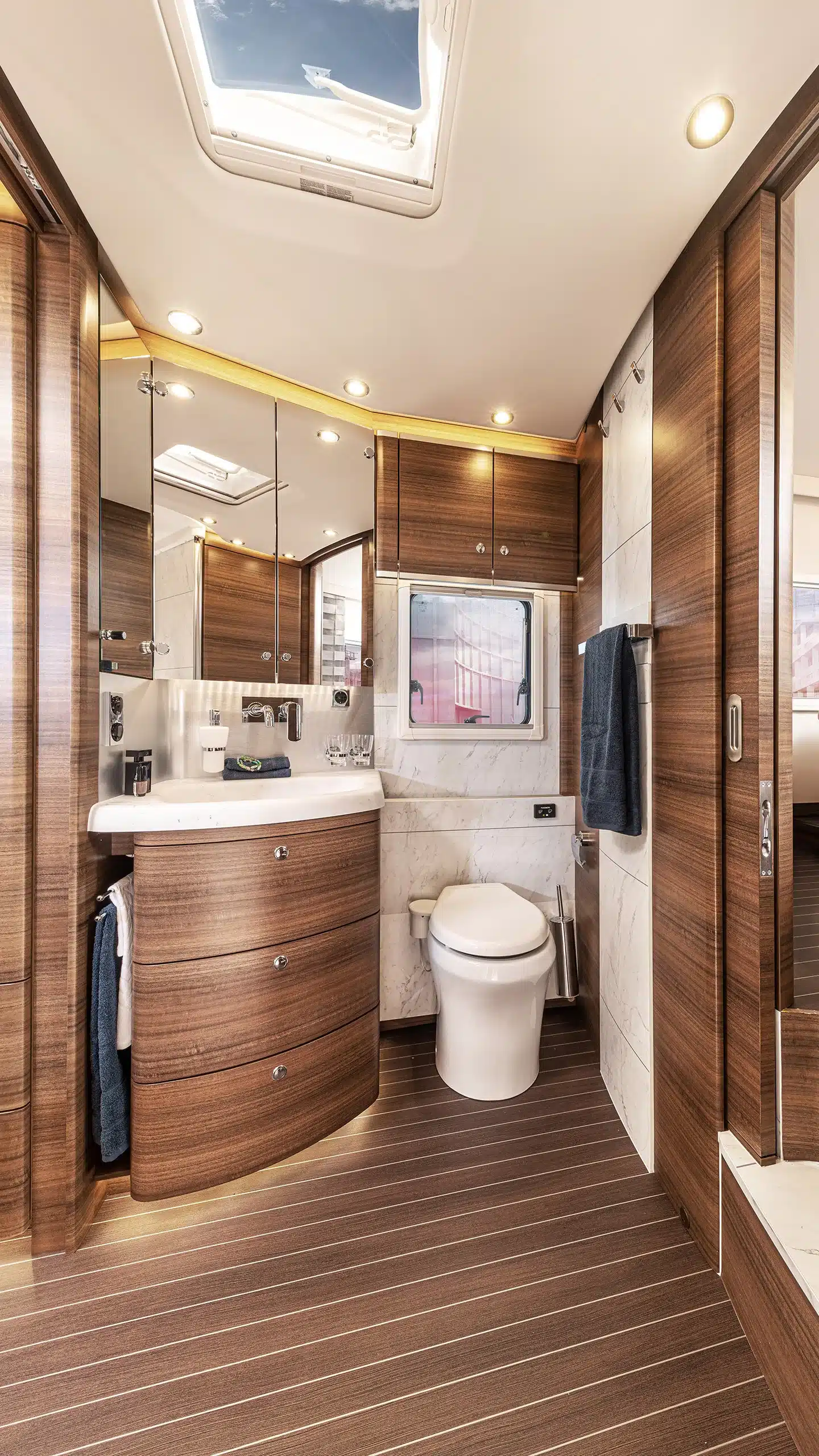 Badezimmer eines Concorde Liner Wohnmobils mit Holzdekor, großem Spiegel und moderner Ausstattung