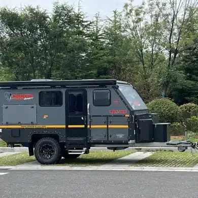Seitenansicht des Conquer Off-Road Trailer 590, angehängt an ein SUV, auf einem Parkplatz mit Bäumen im Hintergrund.