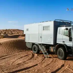 Expeditions-LKW von Delta Automotive auf Sanddünen unter blauem Himmel