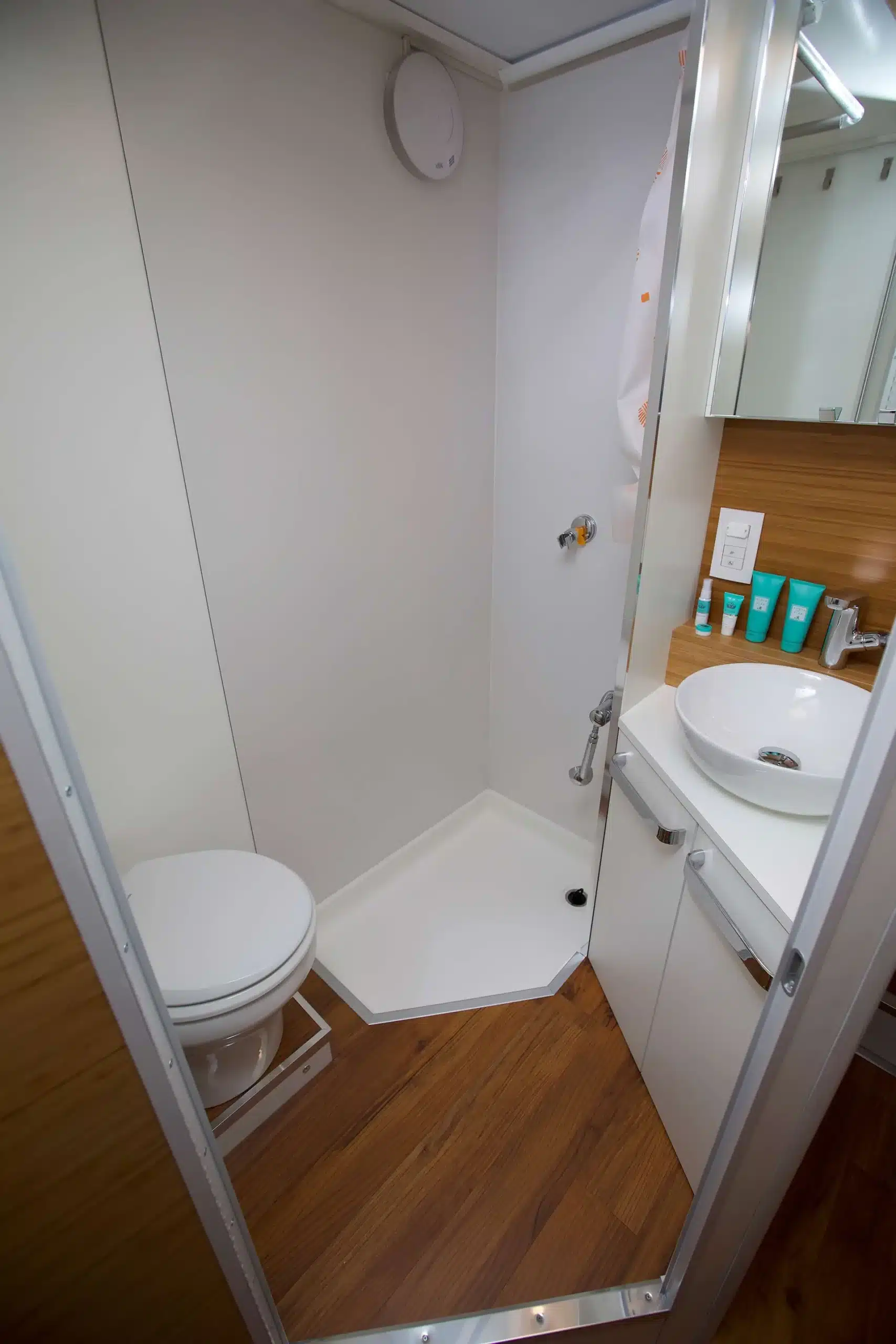 Hochwertiges Bad mit WC, Dusche und Waschtisch im Expeditions-LKW, modernes Design und edle Materialien.