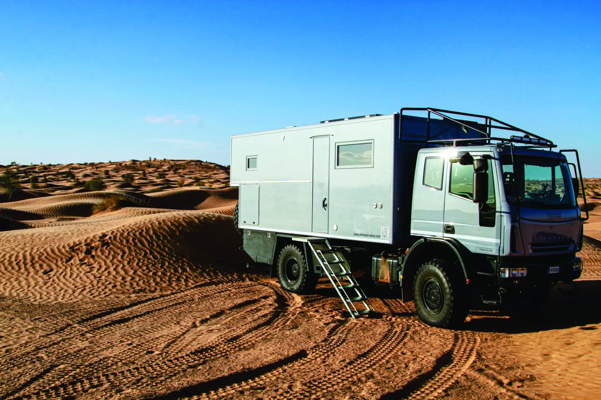 Expeditions-LKW mit Wohnkabine von Delta Automotive auf sandigem Wüstenuntergrund