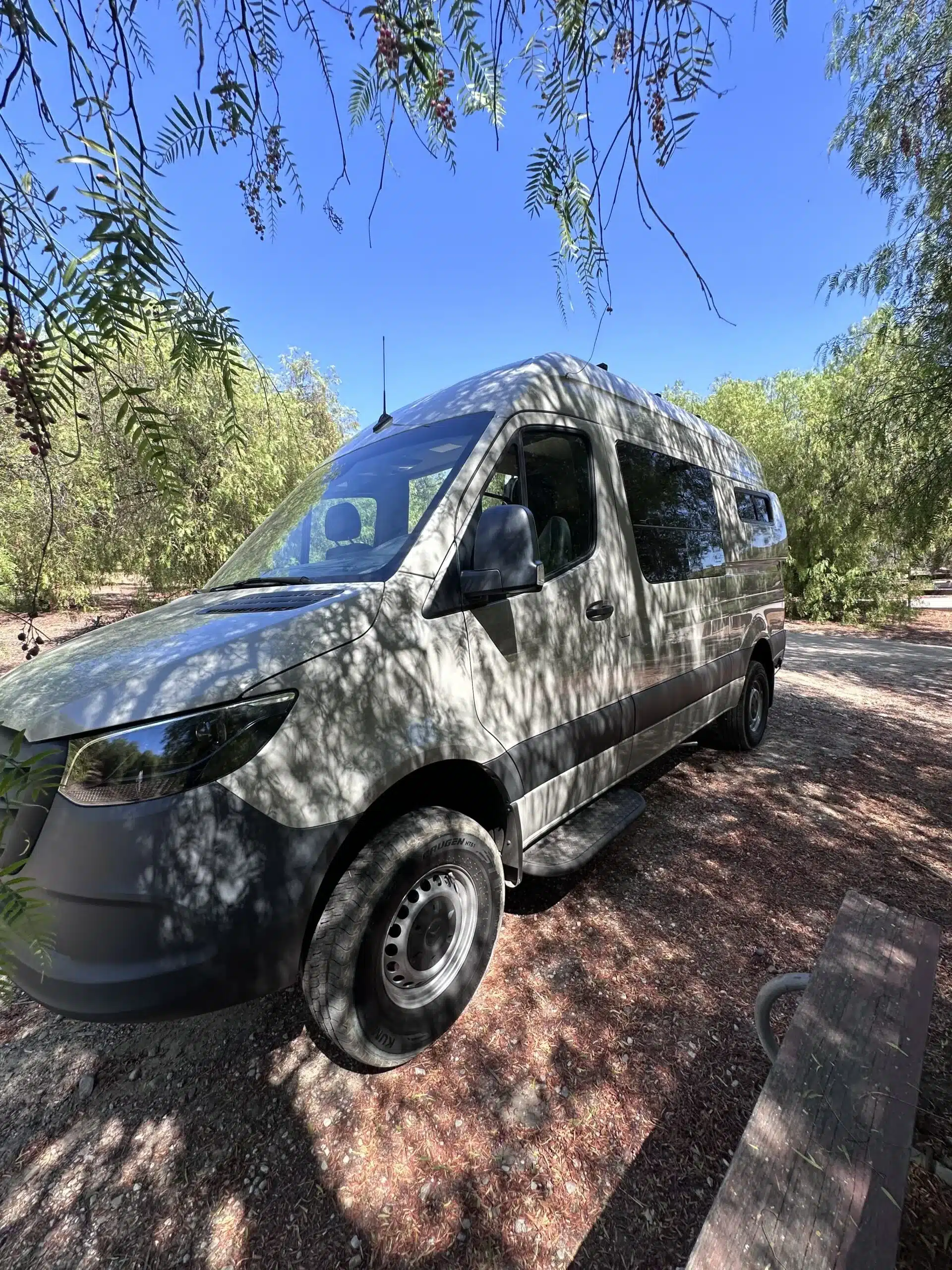 Barrierefreier Mercedes Sprinter Campervan, geparkt im Schatten, von Bäumen umgeben