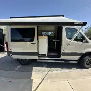 Seitliche Ansicht eines Jet Adventure Vans mit ausgefahrener Markise und geöffneten Türen.