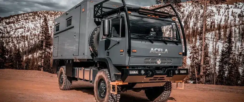 Expeditionsfahrzeug Acela Monterra GL mit Wohnmodul auf unbefestigtem Weg in bergiger Winterlandschaft.