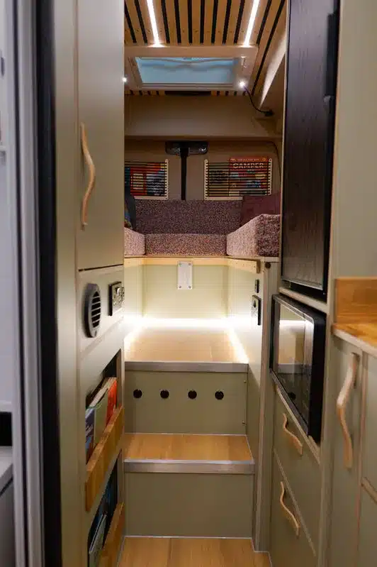 Innenansicht eines individuell ausgebauten Mercedes-Benz Campers mit Schlafbereich und Stufen