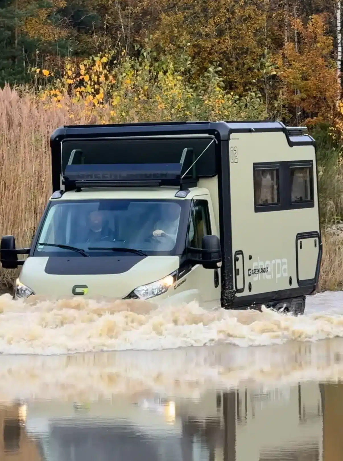 Expeditionsmobil Greenlander Sherpa beim Fahren durch tiefes Wasser in herbstlicher Natur.